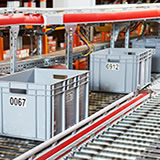 Bins move on a conveyor belt to collect products in a fulfillment center