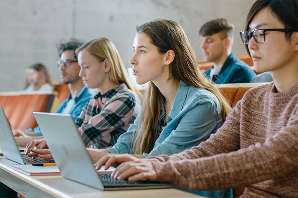 Students with laptops take notes during a class
