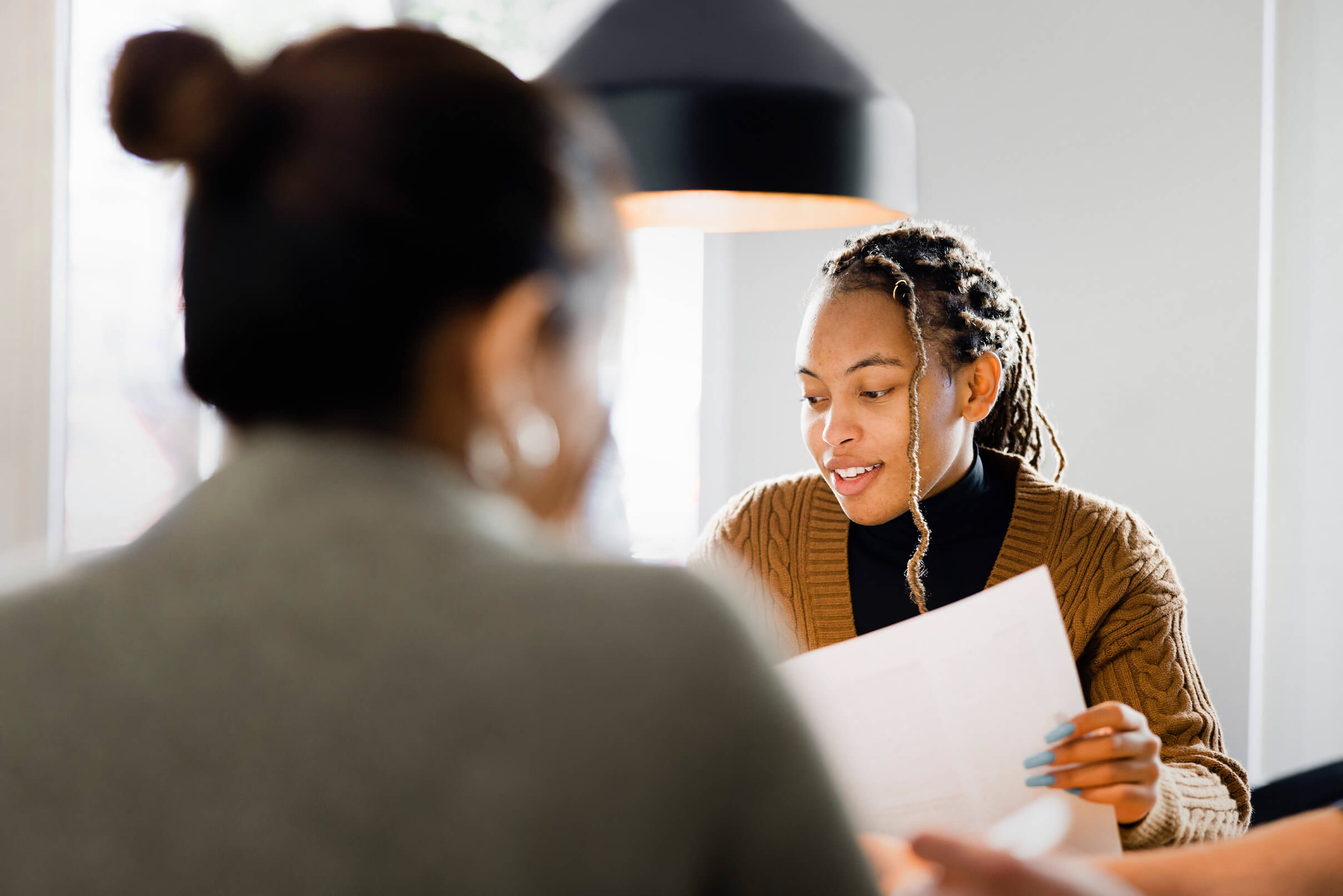 Image of two women having a conversation in workplace setting.