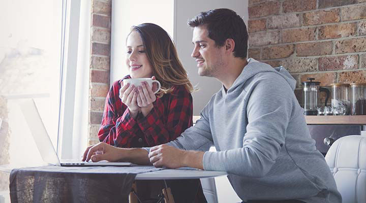 Young couple creating family budget on laptop computer. Indoor image at kitchen
