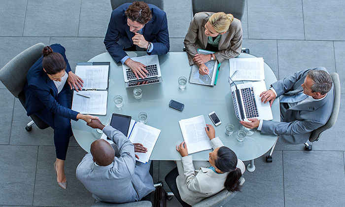 High angle view of businesspeople shaking hands at conference table in office