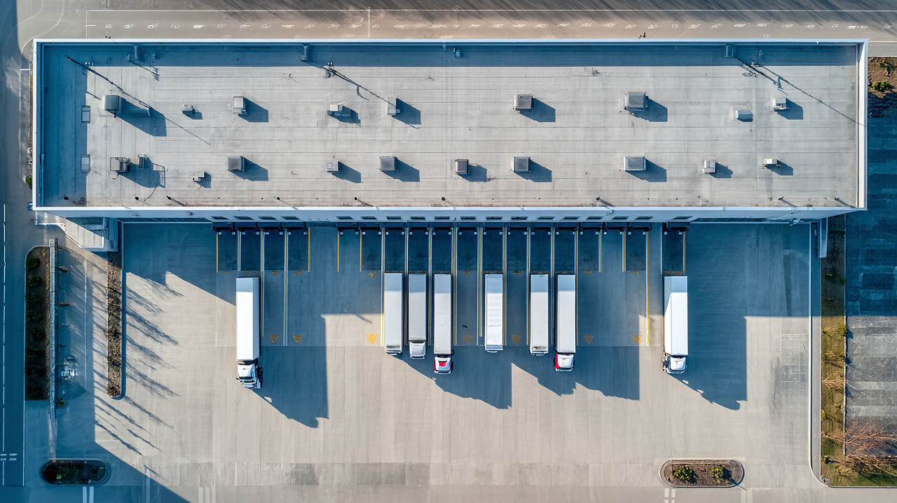 Aerial view of a warehouse roof and loading docks facing a paved truck yard.