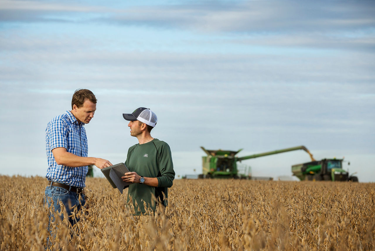 Representative and farmer talking in soybean field