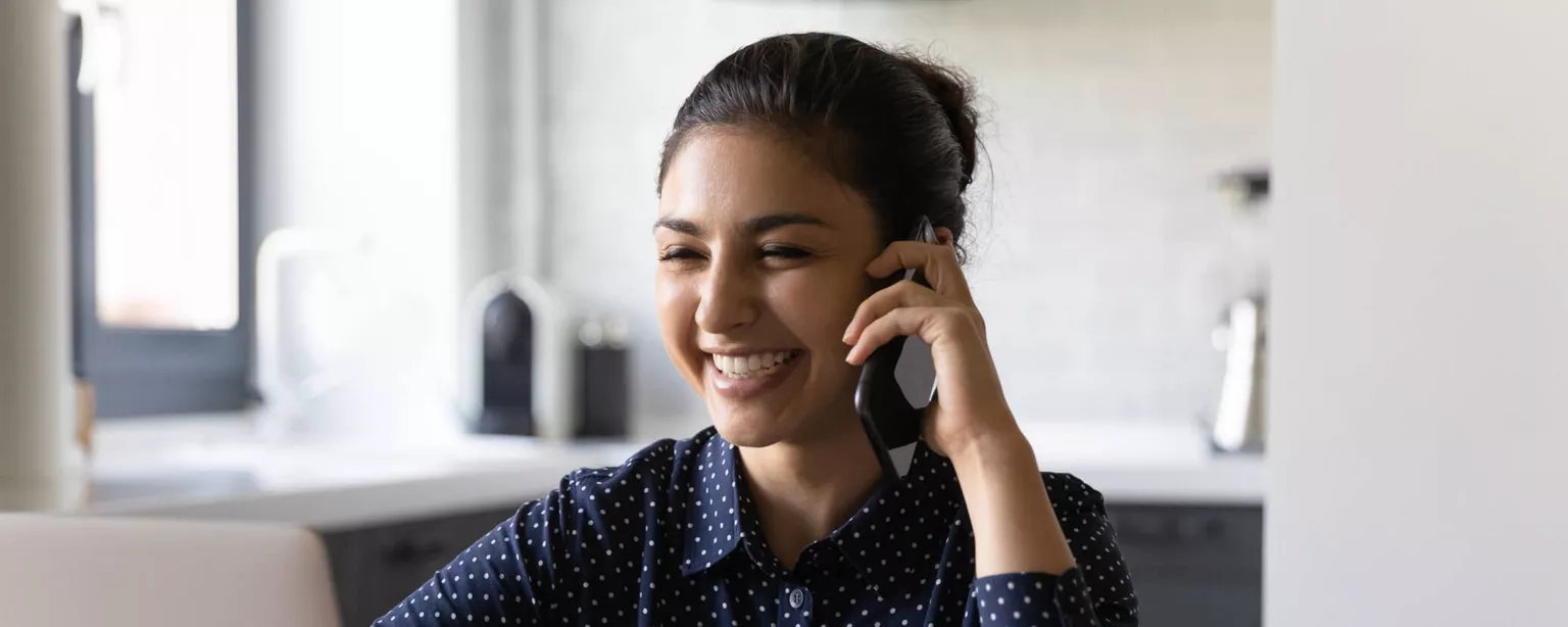 The Power of Praising Your Administrative Professionals — smiling woman on phone in front of laptop
