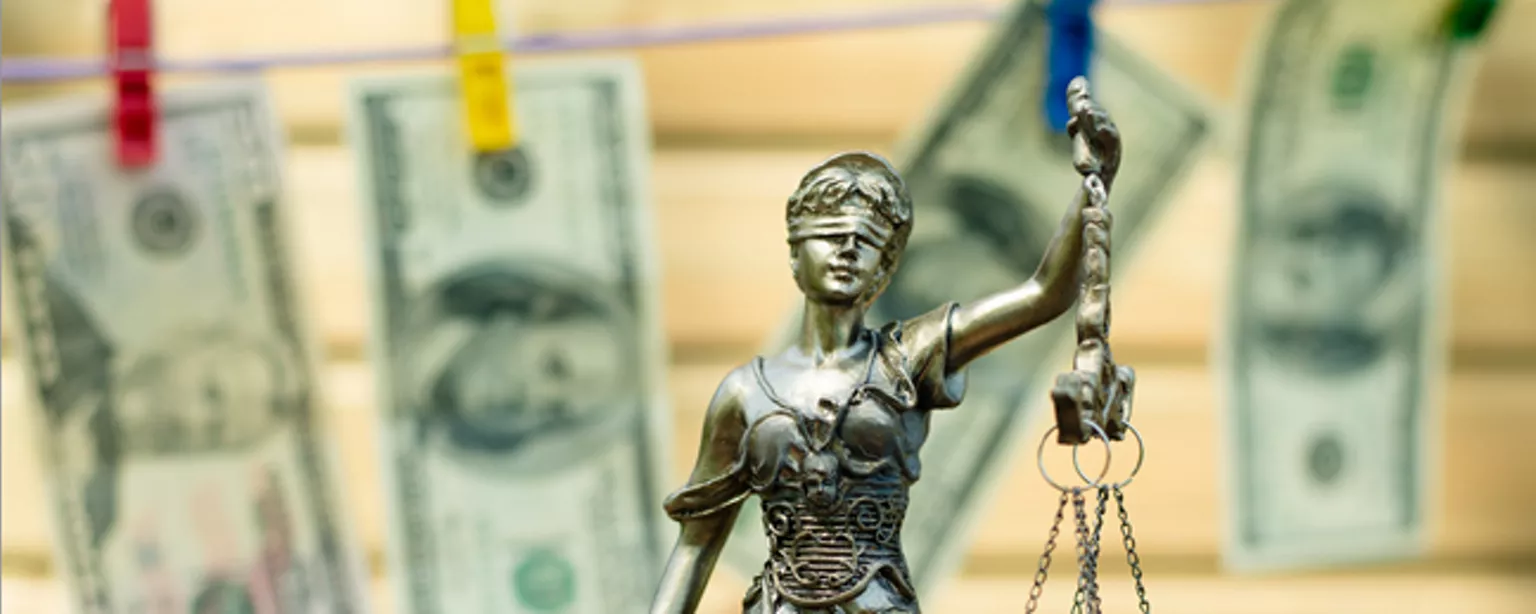Statue and cash on clothesline symbolizing need for anti-money laundering jobs