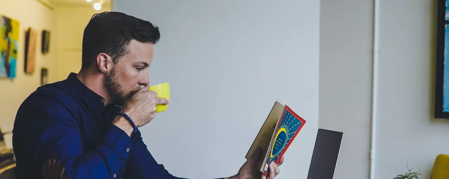 Homem olhando revista e tomando café