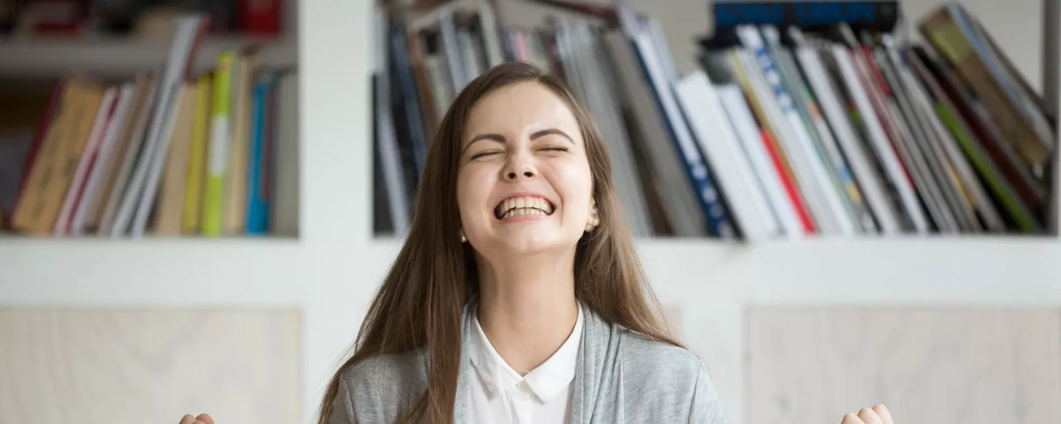 2 Pro Tips to Help You Land a Job Offer Faster - Smiling woman sitting in office at computer.