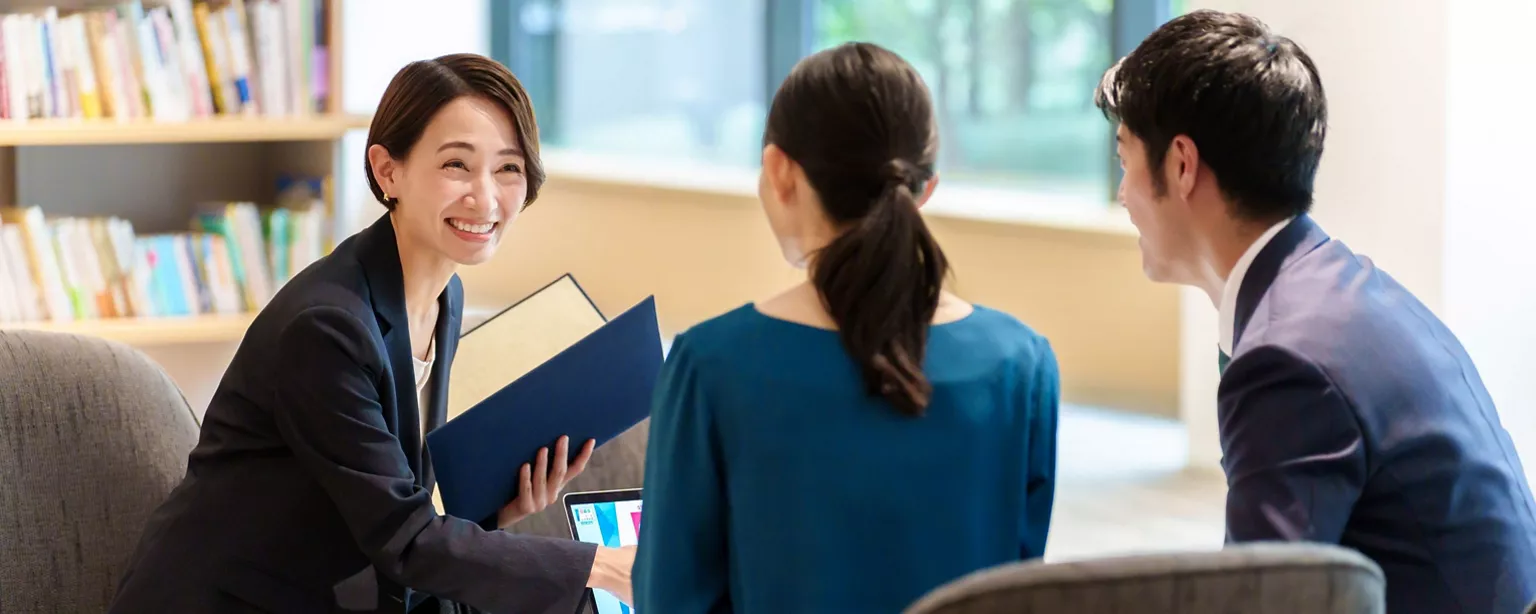 A lady sitting on the sofa talking with a man and a woman in the office