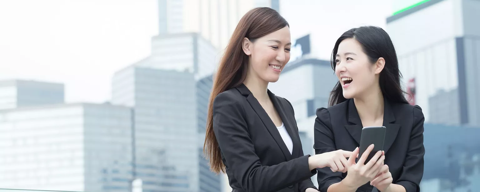 Two office ladies talking happily outside the building