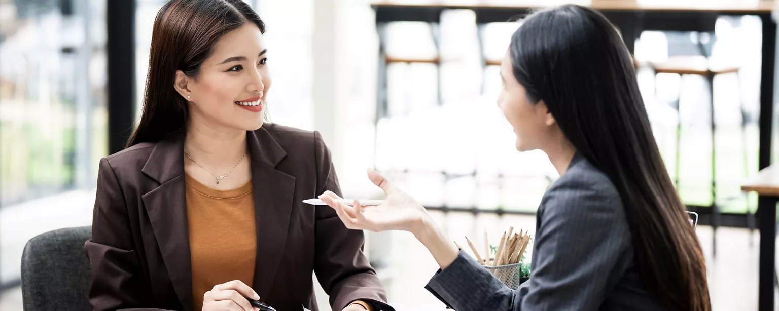 Two office ladies talking happily in the office