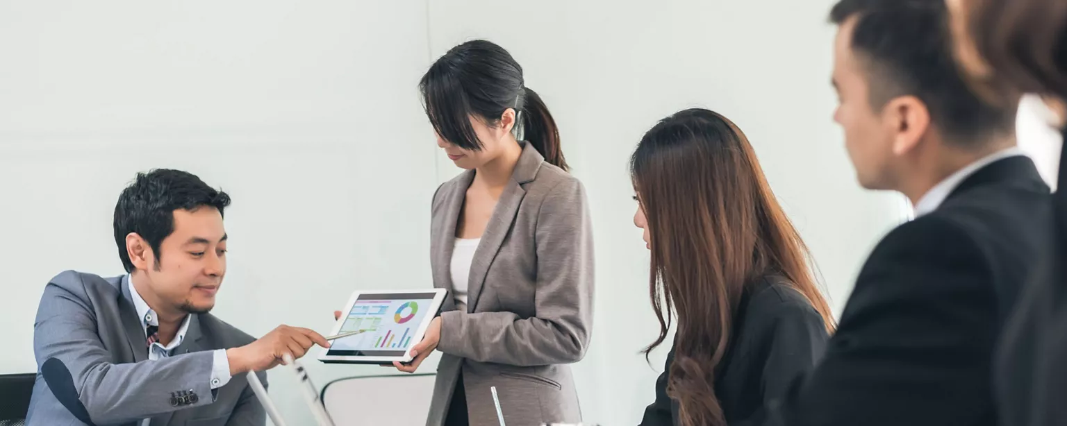 A manager is demonstrating AI tools to several professionals in the workplace.