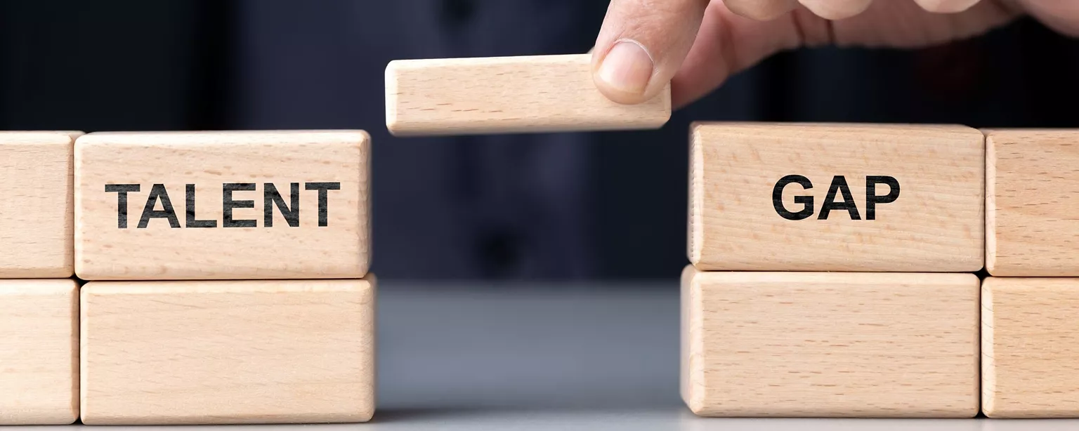 A person building with blocks on a block bridge illustrates the talent gap