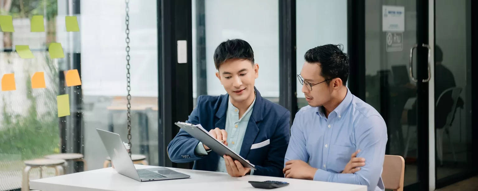 Two male office workers are discussing an issue in the office