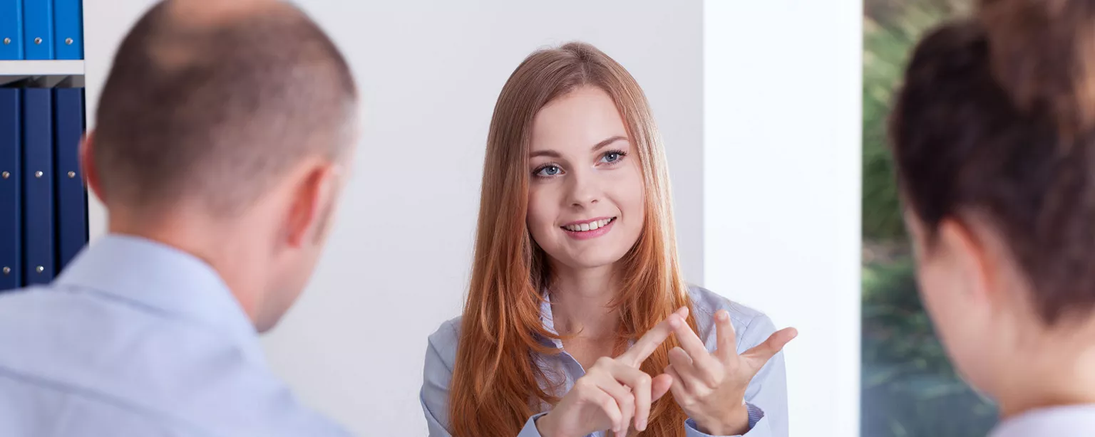 Female hiring manager sitting across a desk from a man and a woman.