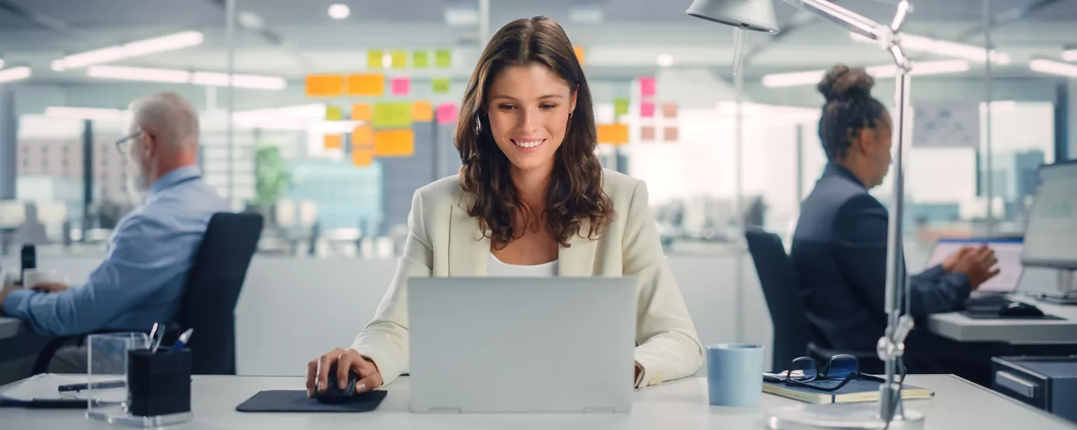 An office worker is the model of efficiency as she enjoys her tasks at the computer, in part because of her optimized approach to work.