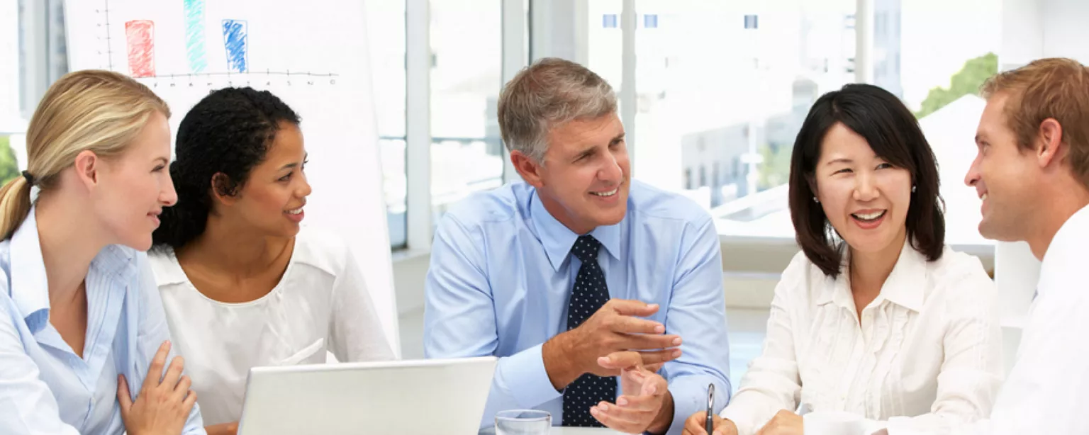 Five business people having a positive discussion in a meeting room.