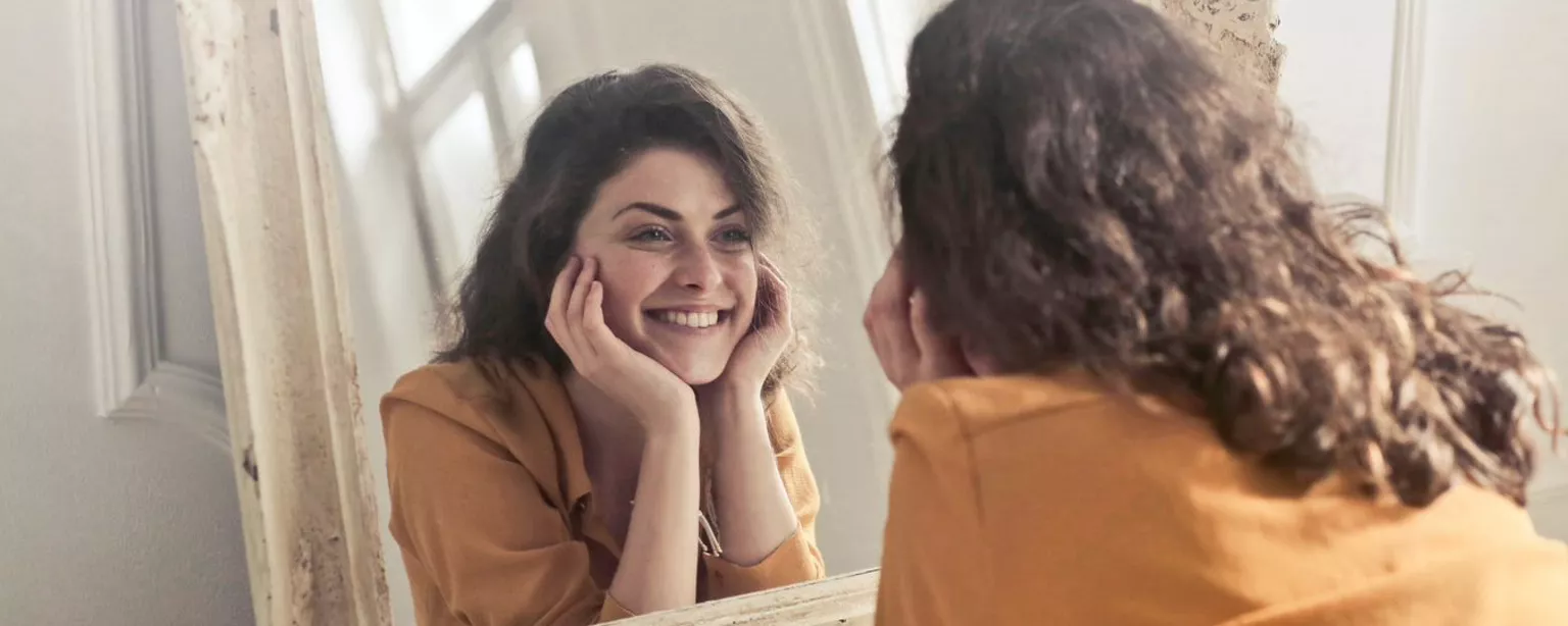 mujer feliz mirando en el espejo