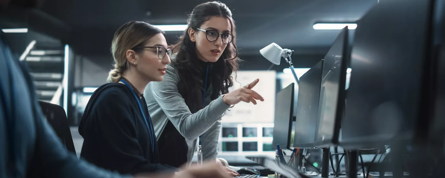 A woman in an entry-level IT role gets some training from another team member.