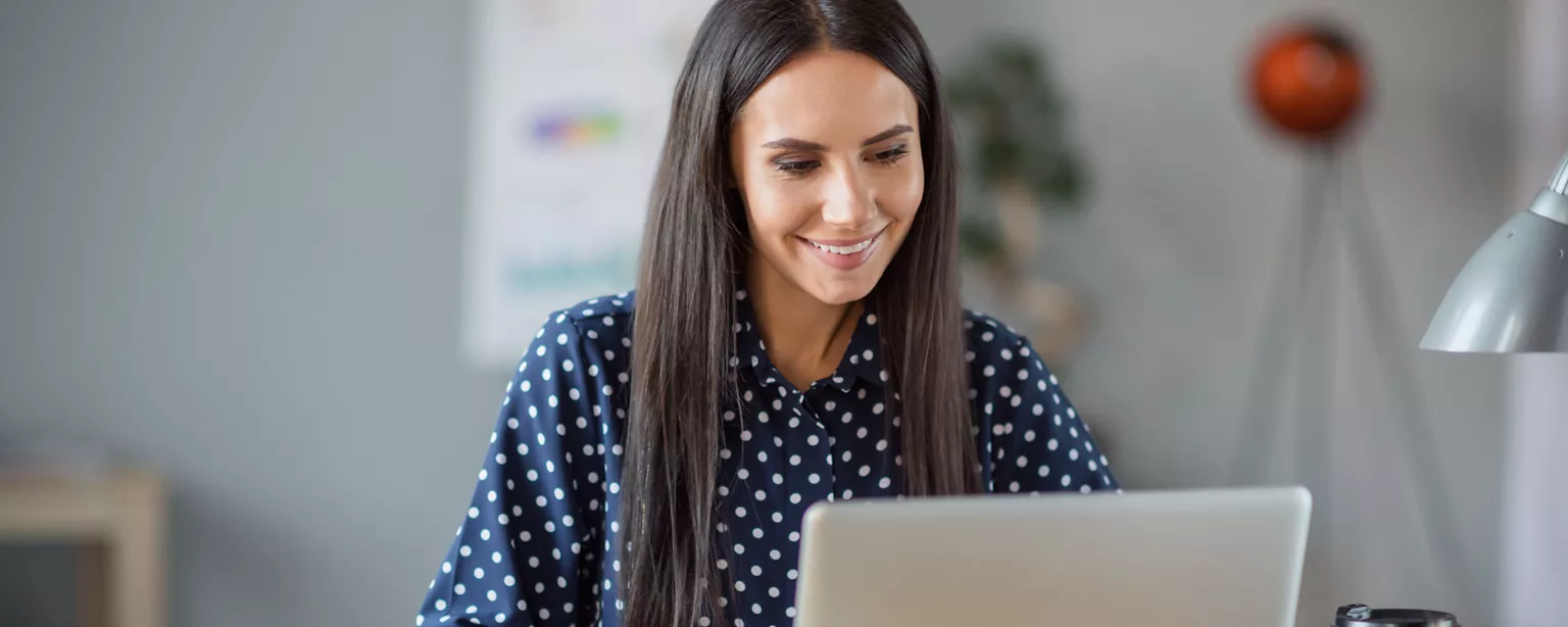 A woman smiles as she prepares her resume, knowing that she's going about it the correct way.