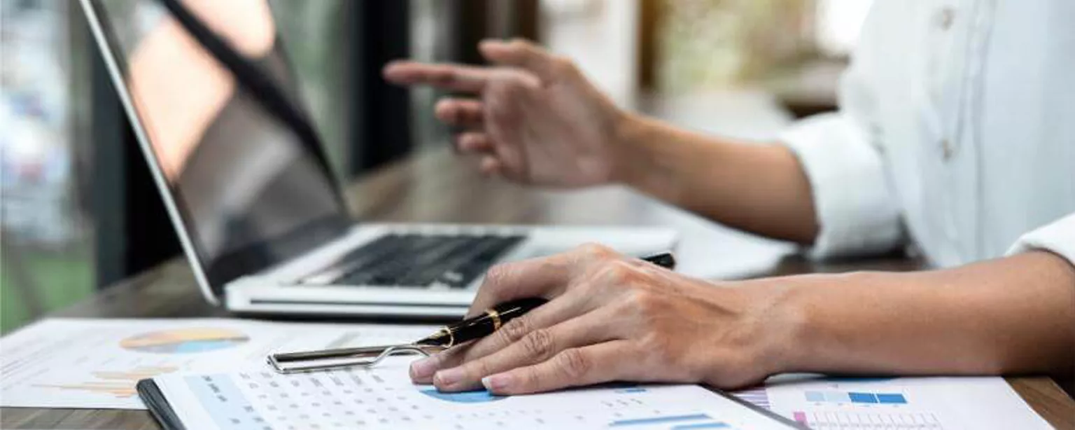 An accounting professional works with laptop and graphs.