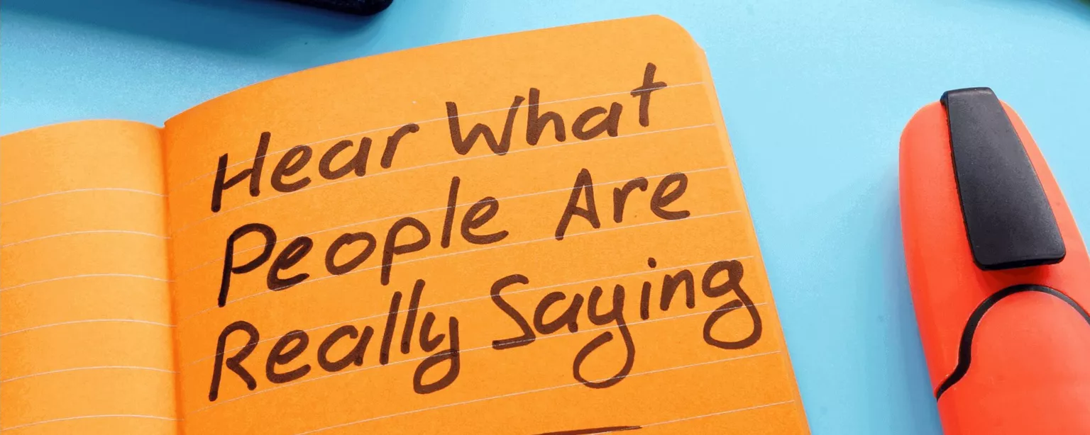An orange notebook page displays the handwritten words, "Hear what people are really saying."