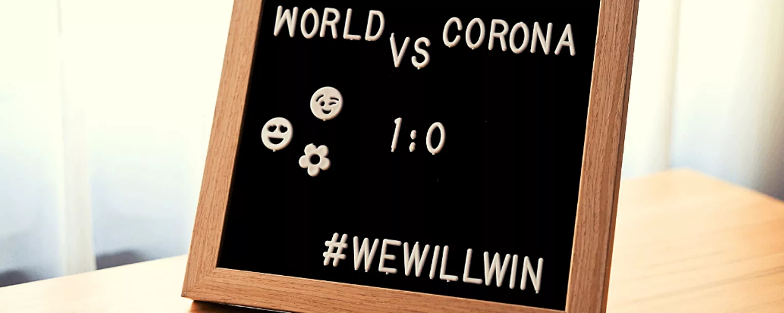 Tafel mit Aufschrift, Emotys und Hashtag: World vs. Corona 1:0 #WeWillWin