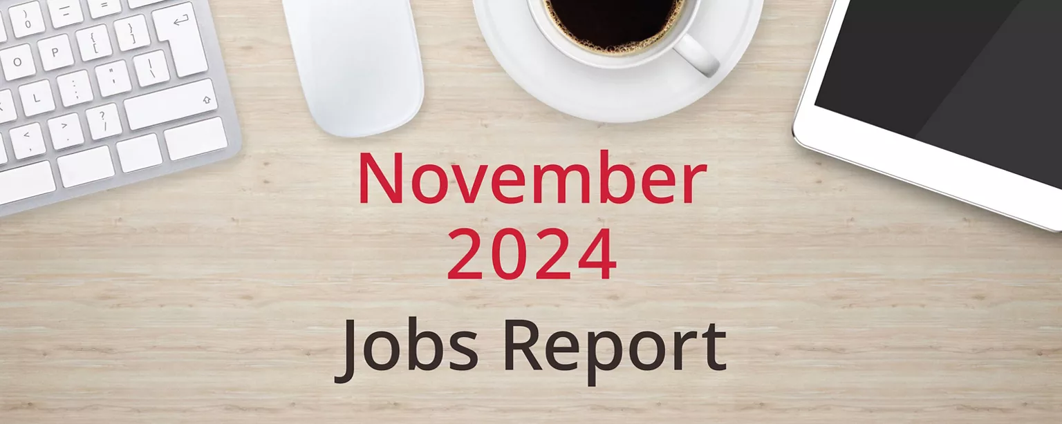 On a wooden desktop, positioned below a keyboard, mouse, cup of coffee and a tablet computer, are the words, 'November 2024 Jobs Report."