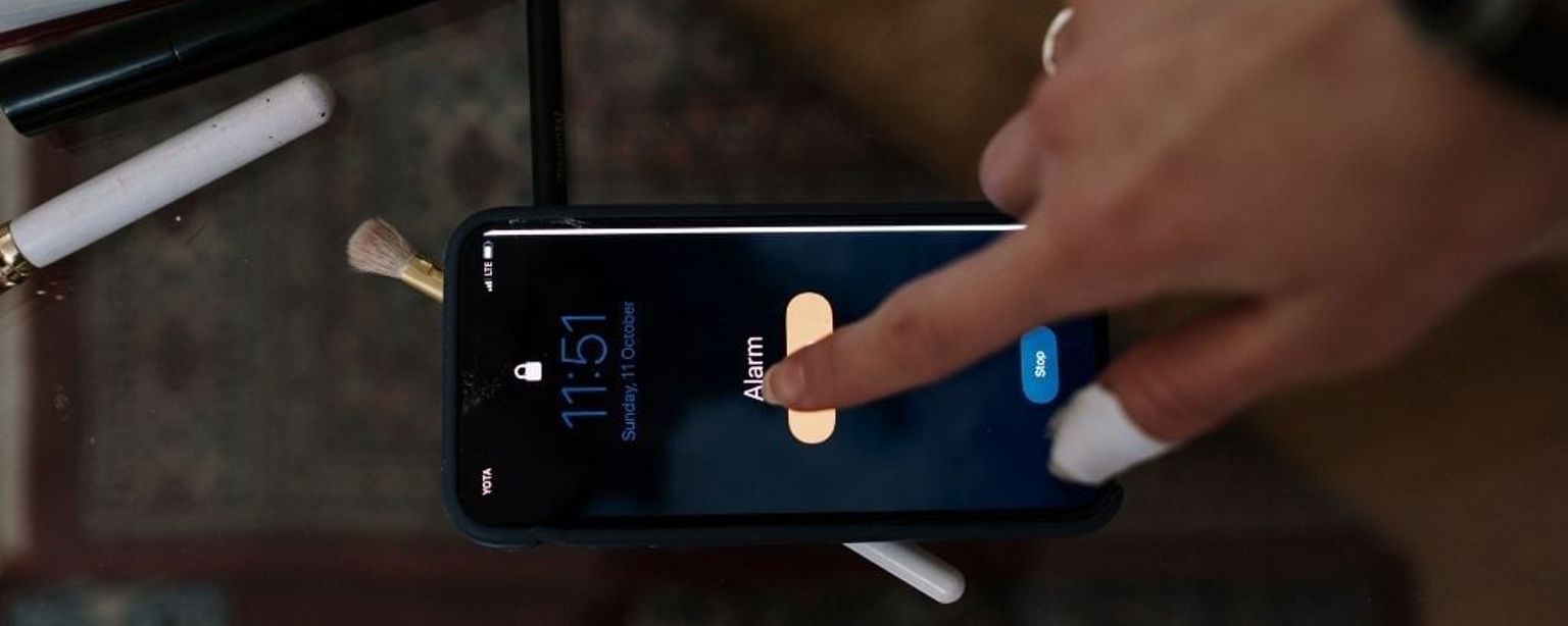 Frauenfinger macht Alarm auf dem Smartphone aus.