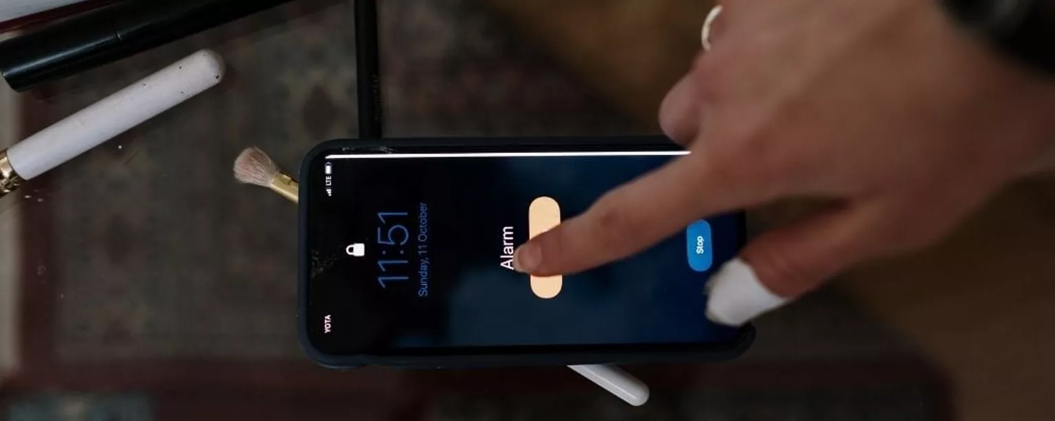 Frauenfinger macht Alarm auf dem Smartphone aus.
