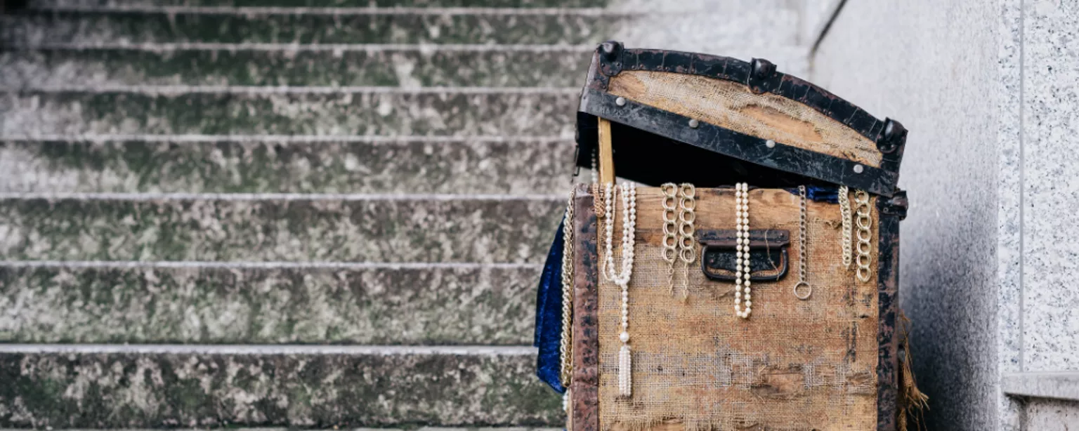 Alte, halb geöffnete Schatztruhe, aus der mehrere Ketten heraushängen