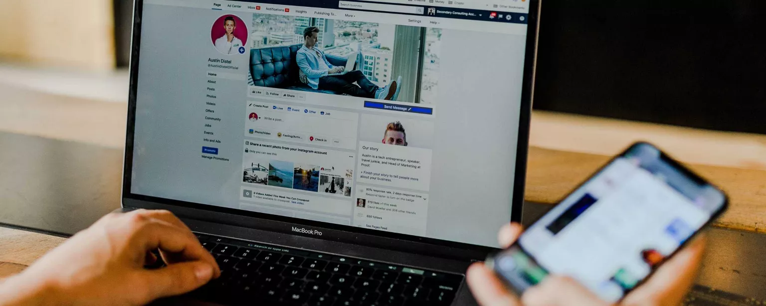 Laptop mit Social Media Profil und Handy in der Hand