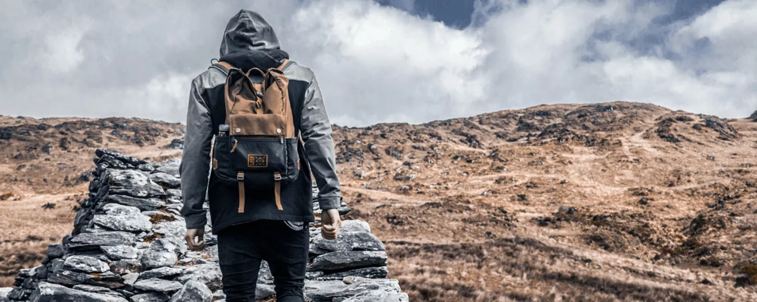 Rückansicht eines Wanderers, der einen Felsweg im Gebirge erklimmt.