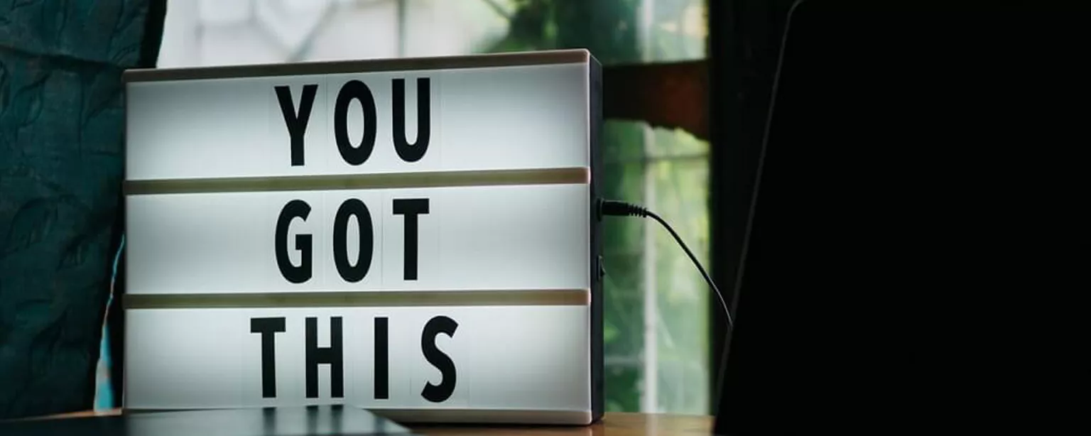 Eine Tafel mit der Aufschrift “YOU GOT THIS”, daneben ein Laptop