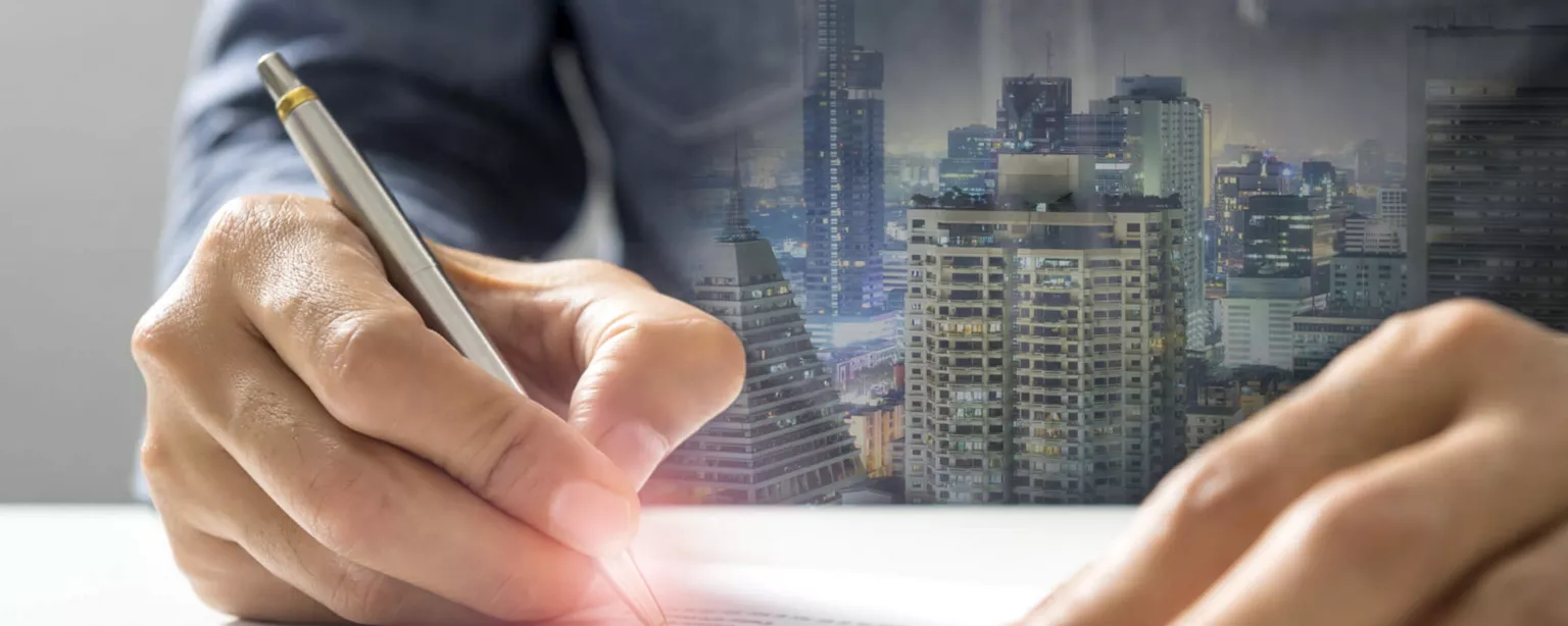 Hand holding pen to calculate bookkeeper salary levels, with city in background