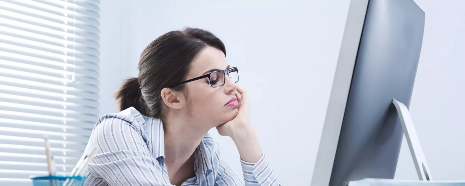 Young woman facing a computer and looking bored. 