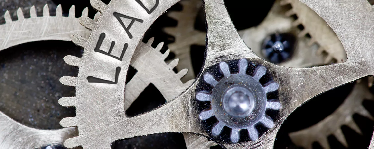 Machine gears with one cog stamped with the word "leadership."