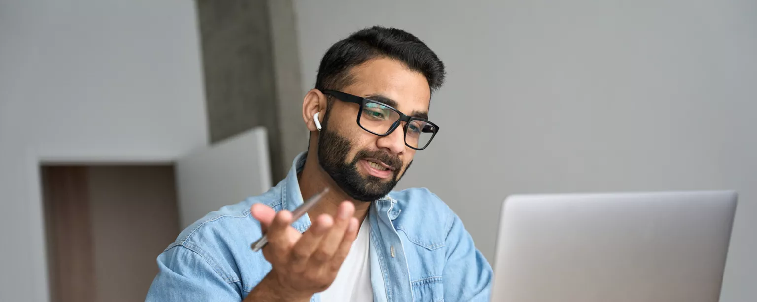 How to Hire a UI Designer — man with laptop wearing ear buds talks during remote call