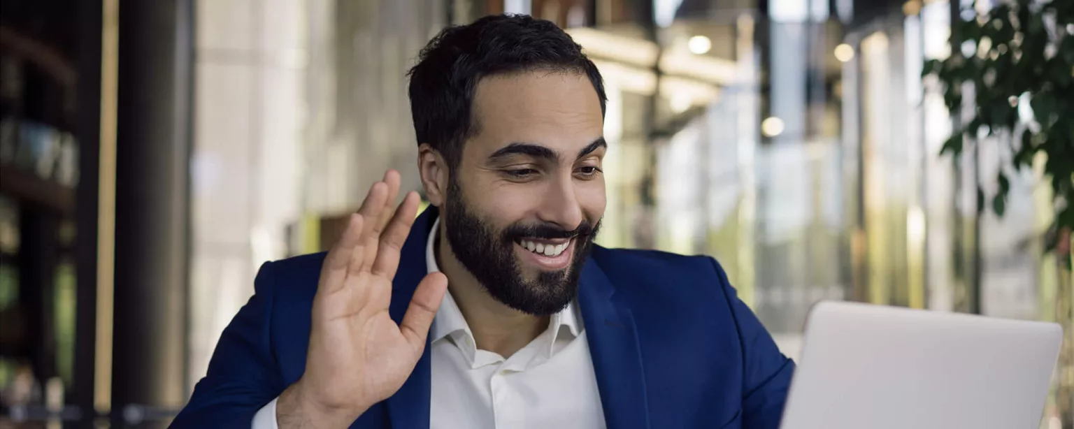 Attract Top Talent With a Great Candidate Experience — man in blue suit coat smiling and waving at laptop