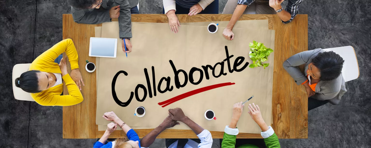 Table of people at table that says collaborate