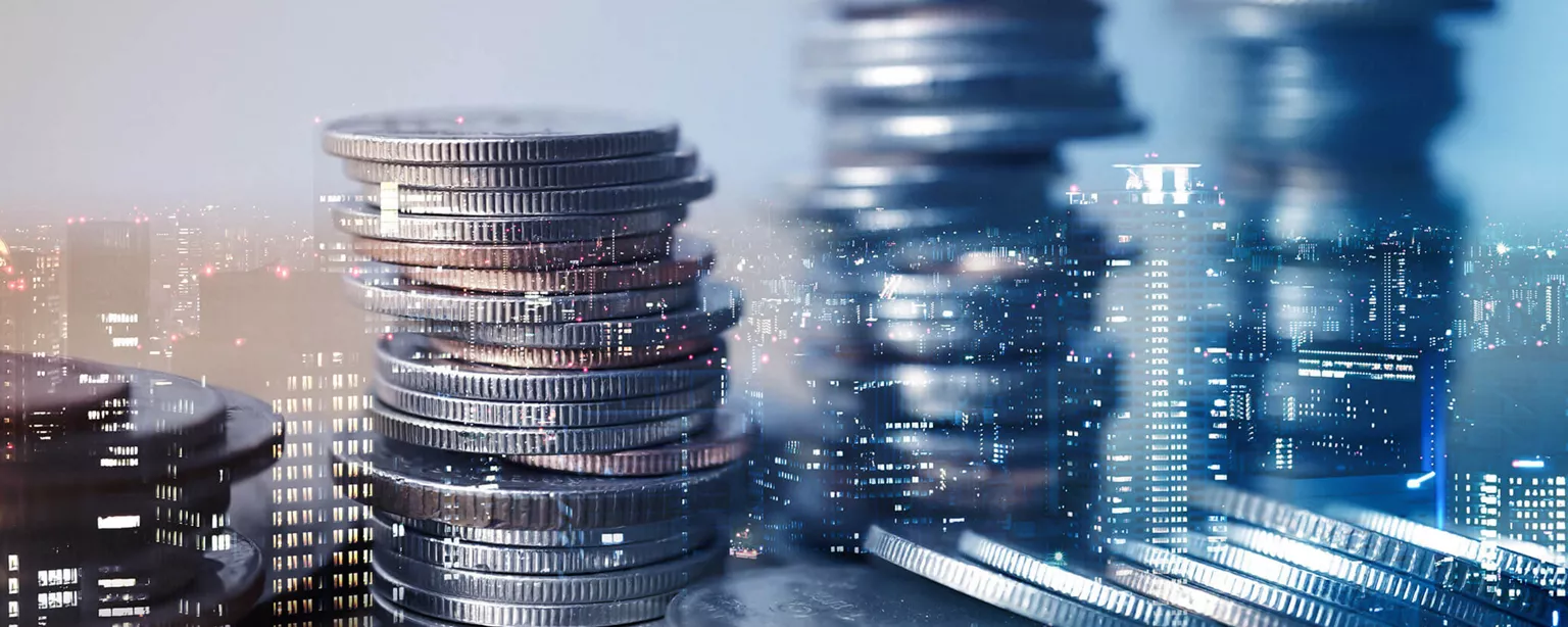 Stacks of coins with city in background representing accounting and finance salaries by city