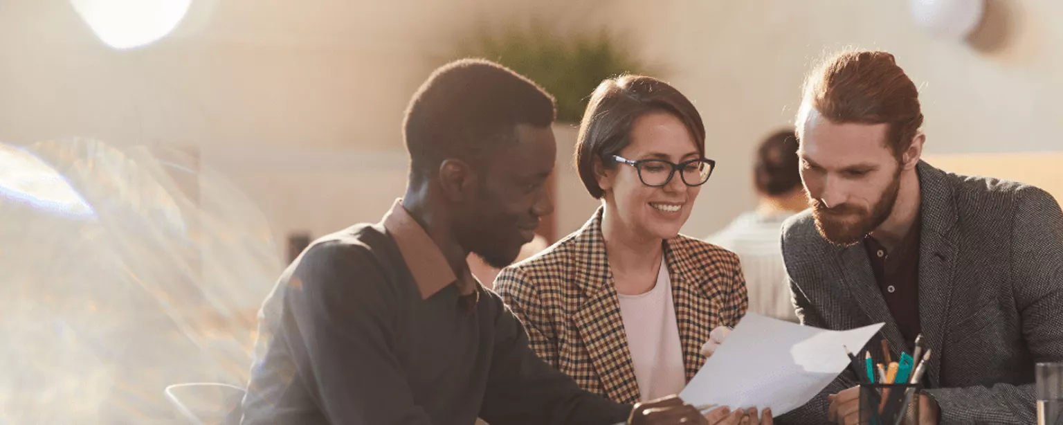 Two men and a woman look over a document together. The Compelling Culture logo appears in the bottom left corner, with the tagline 'Fuelled by engaged and inclusive teams'