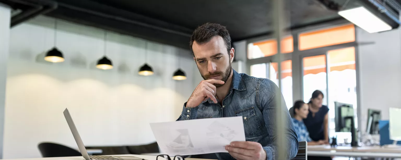 Man at open office desk contemplating hiring a cost accountant