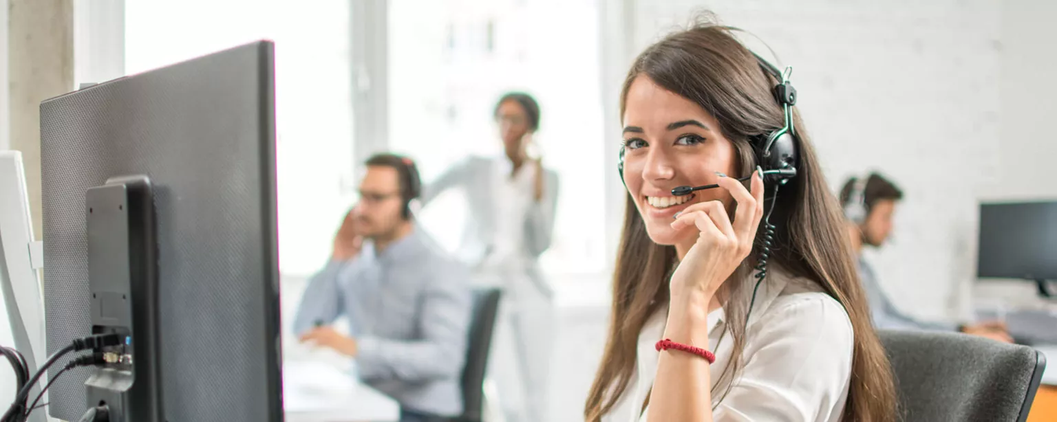 How to Help Your Team Build a Customer Service Mindset — woman wearing earphones at computer in busy office