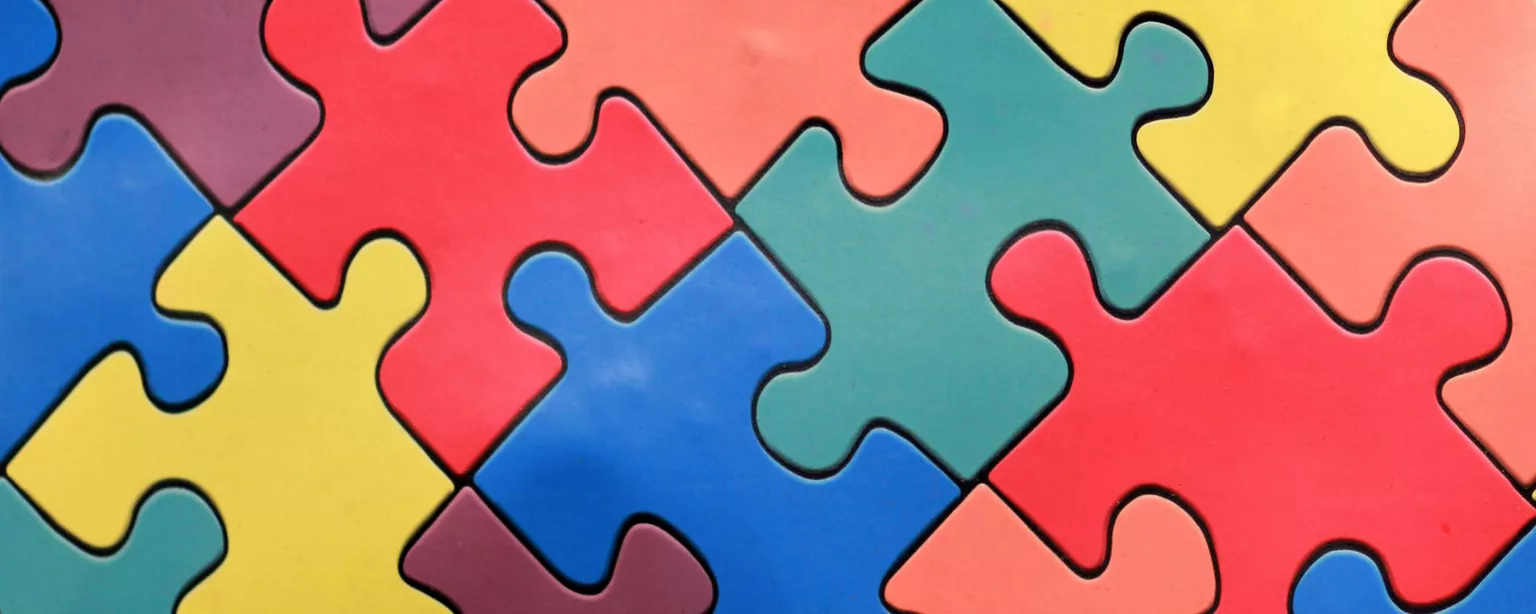 Interlocking puzzle pieces of different colors; diversity, equity and inclusion (DEI) concept.