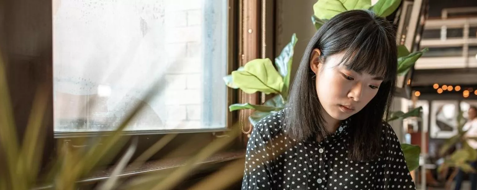 A woman in a black spotted shirt reviews documents and updates her CV