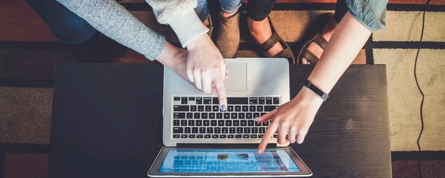 Mehrere Personen zeigen auf einen Laptop