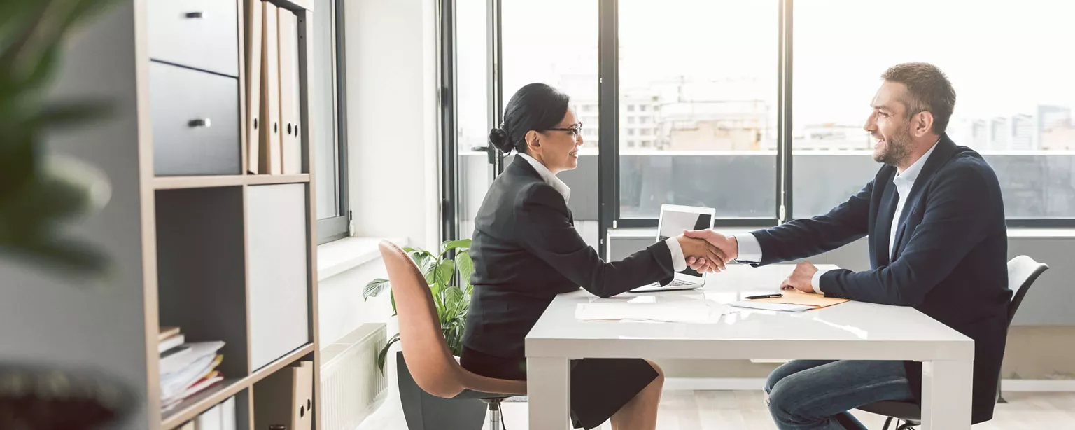 A hiring manager at a large enterprise shakes hands with a new employee.