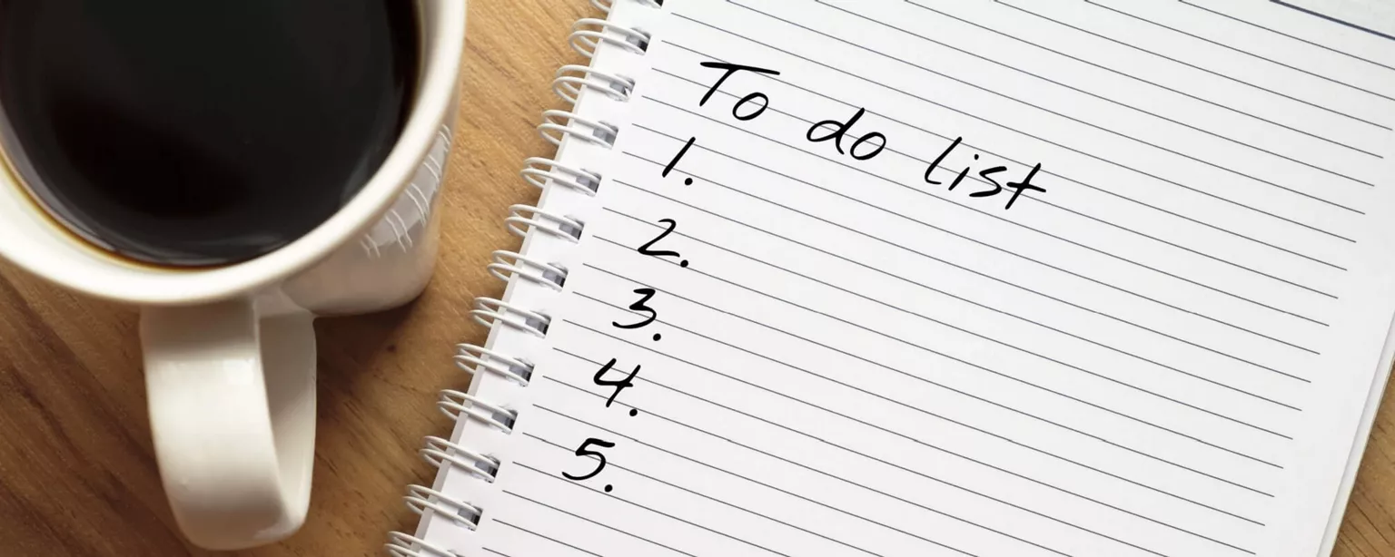 A cup of coffee next to a note pad and pen; the notepad reads, "To do list" and includes the numbers 1-5.