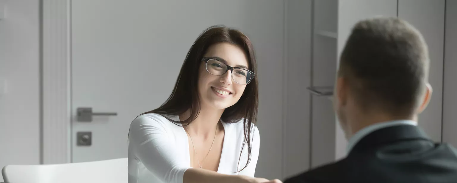 Two people shaking hands at desk, as a financial controller is hired
