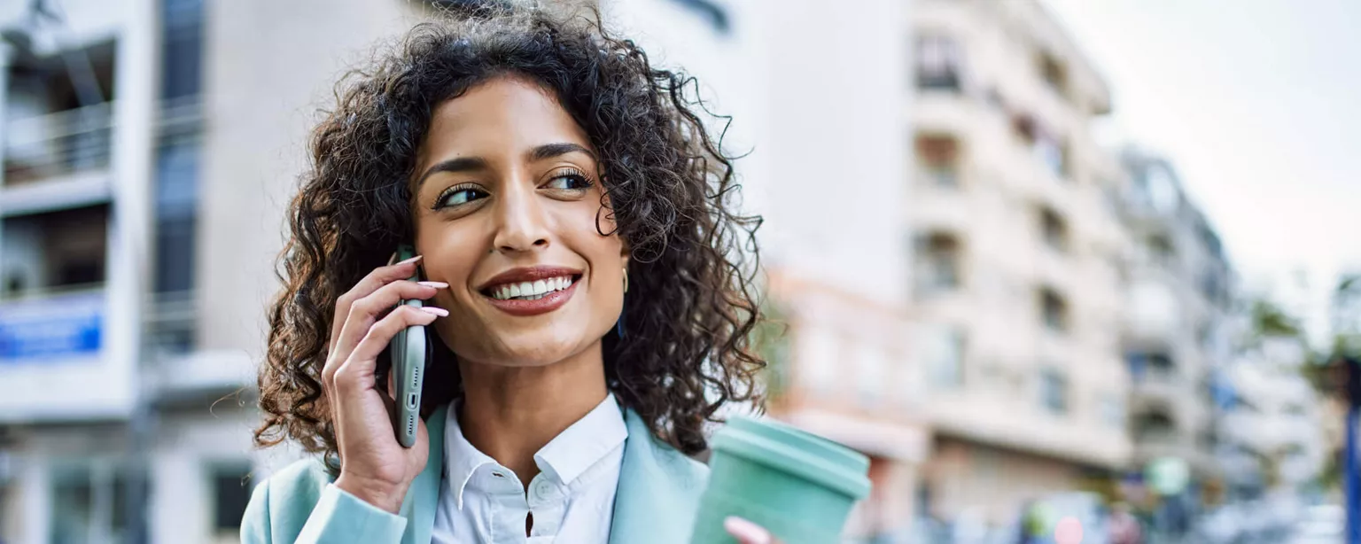 Forbes Names Robert Half as One of World’s Best Employers — professional woman with phone and coffee walking outside